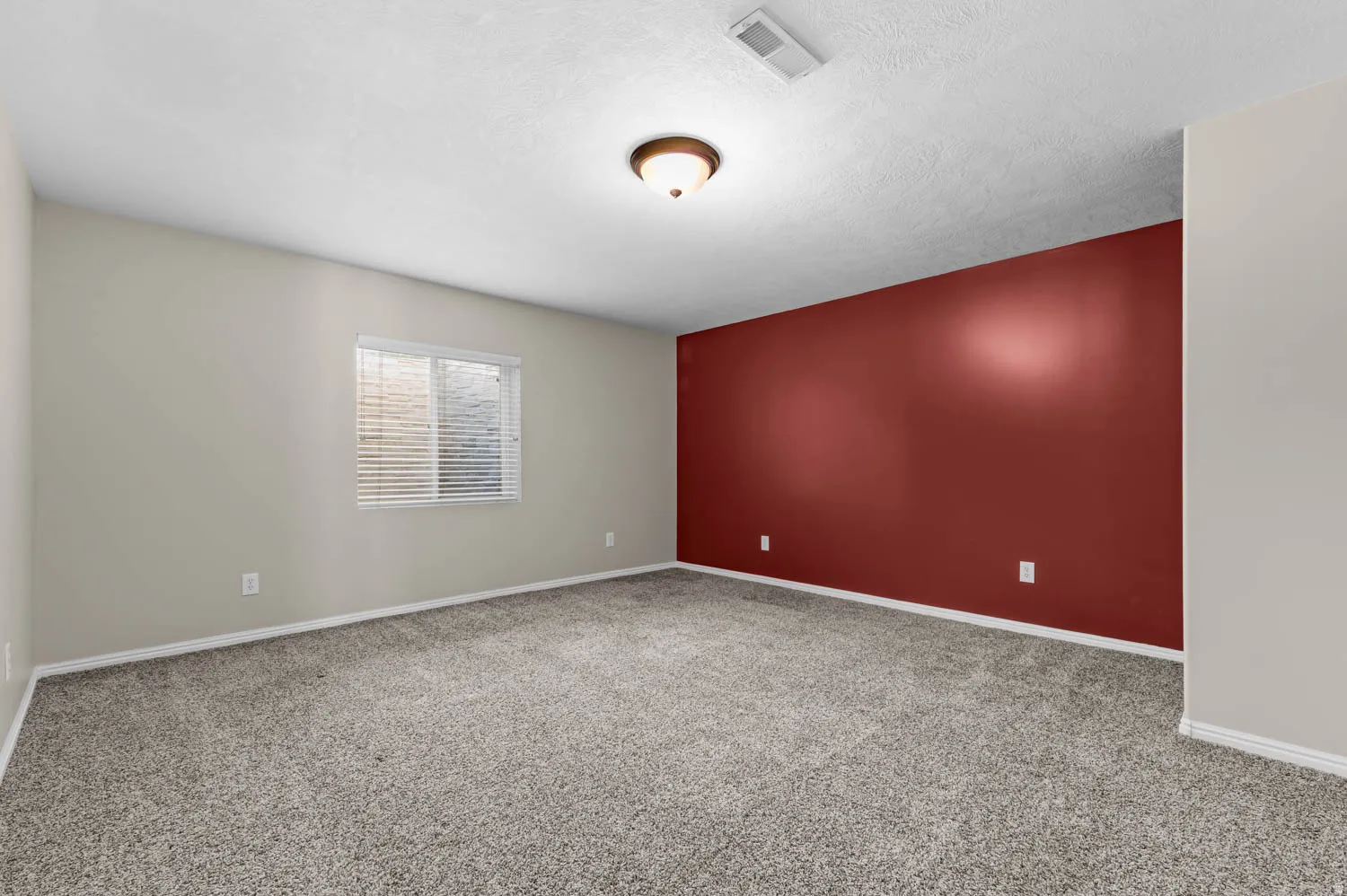 Spacious room featuring carpeting, a painted accent wall, and a window with blinds