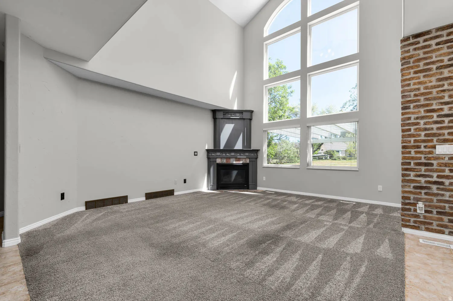 Two-story living area featuring a prominent window wall with an arched top frame