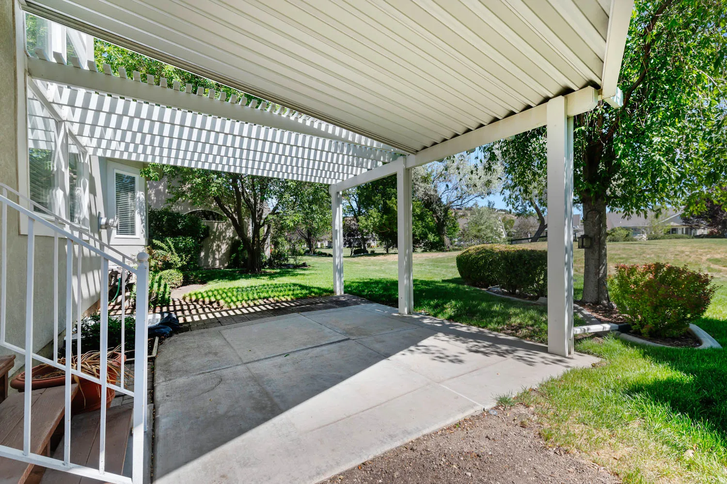 Covered patio with a slatted pergola extension and a concrete surface