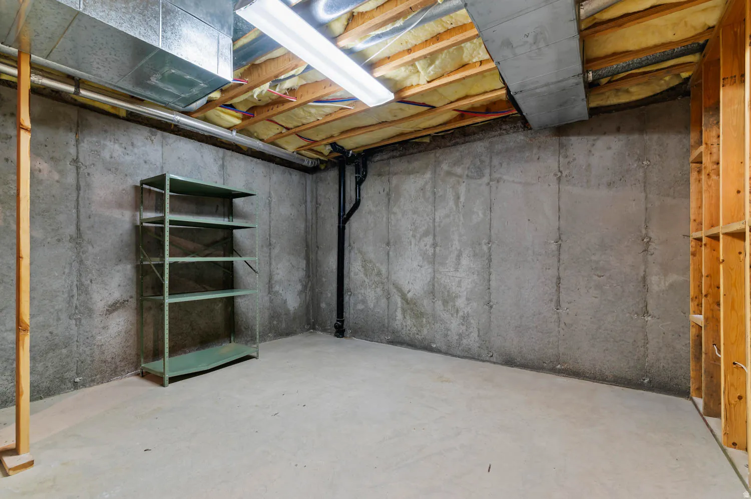 Unfinished basement space featuring concrete walls and flooring, exposed ceiling joists with insulation, and visible ductwork
