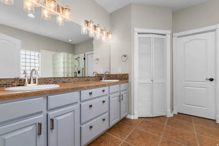 Dual vanity with integrated sinks and brushed nickel faucets, set against a mosaic tile backsplash