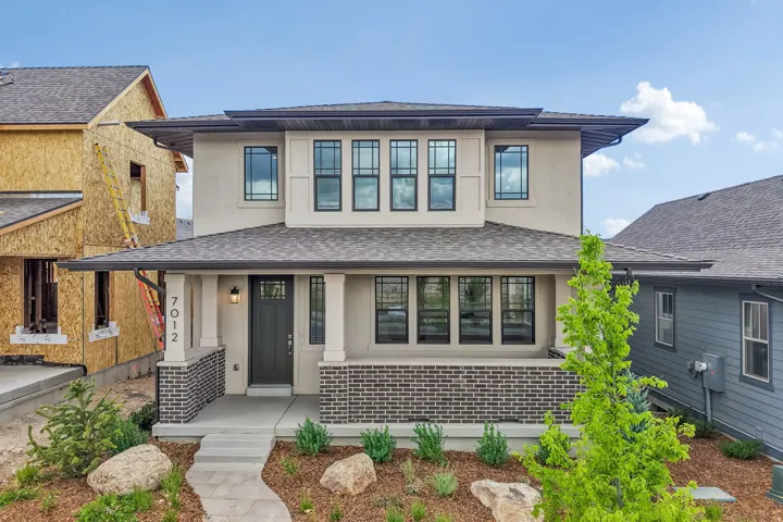 Contemporary architectural facade featuring a covered front porch, dark brick accents, and a dark asphalt shingle roof