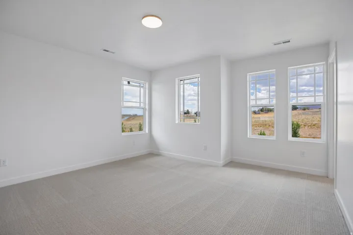 Spacious room featuring light gray carpeting and white walls