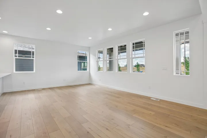 Bright interior space featuring wood-finish flooring, recessed lighting, white walls, and multiple windows with white trim