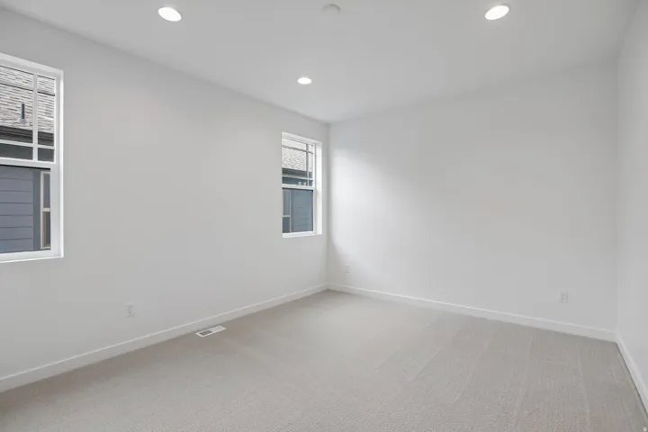 Carpeted room featuring two windows with white trim, recessed lighting, and white baseboards