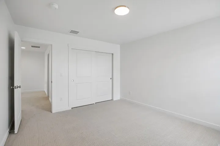 Neutral-toned wall-to-wall carpeting complements the bright white walls