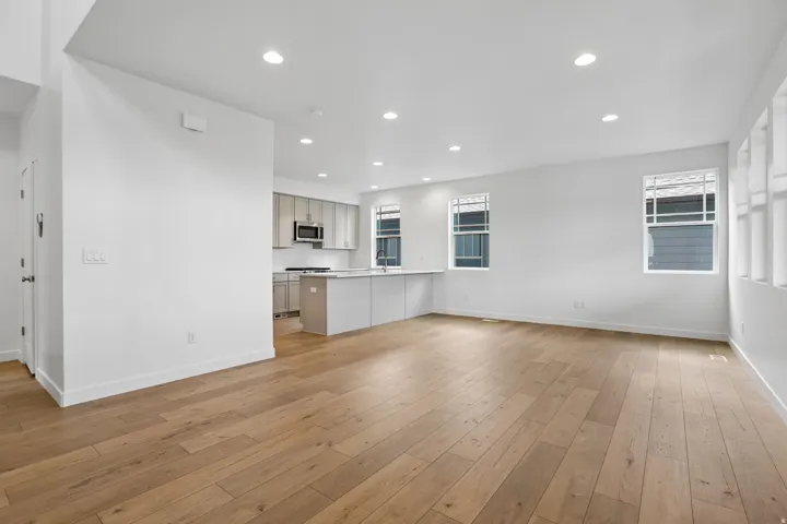 Open-concept living area featuring wood-finish flooring, recessed lighting, and bright white walls