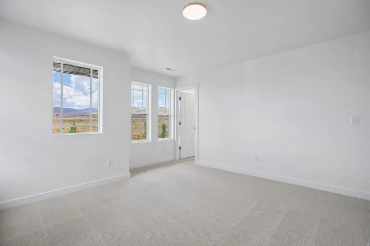 Bright room featuring three windows, neutral carpeting, white trim, and a flush-mount ceiling light