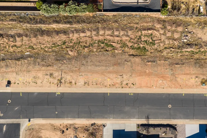 Expansive undeveloped parcel featuring a paved street frontage, concrete sidewalk, and established utility access points
