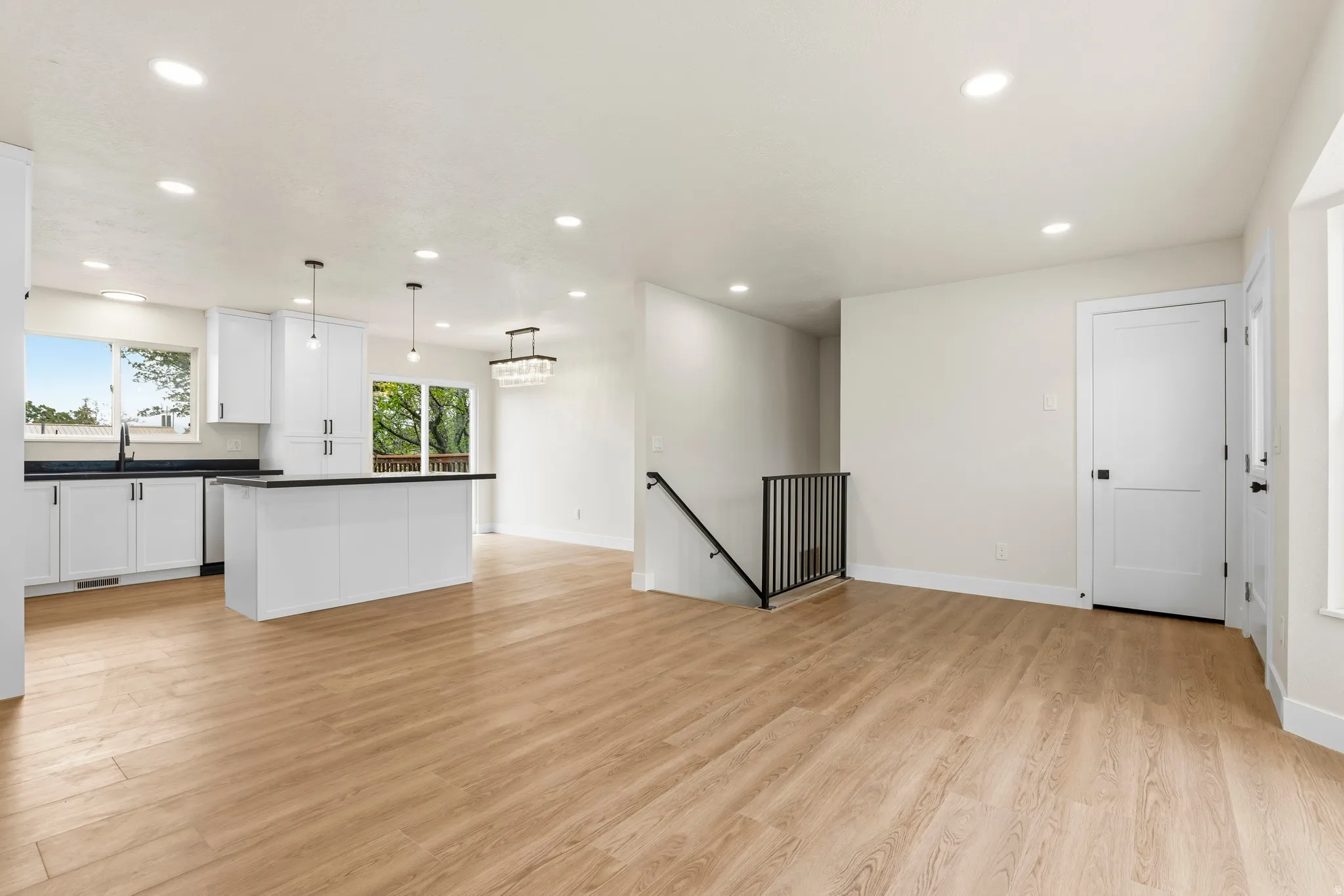 Open-concept living area featuring wood-finish flooring, recessed lighting, and a modern kitchen