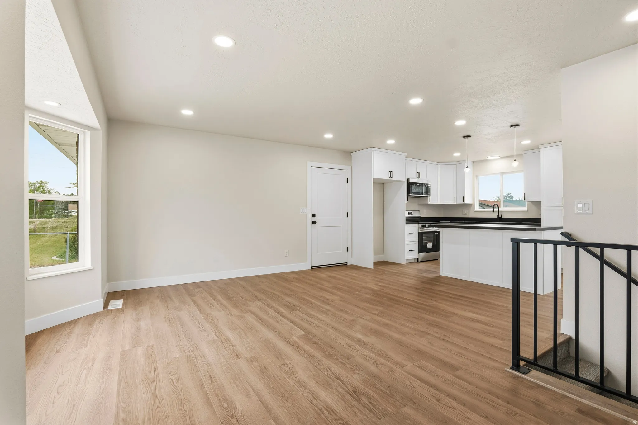 Open-concept living space featuring wood-finish flooring, recessed lighting, and a bay window