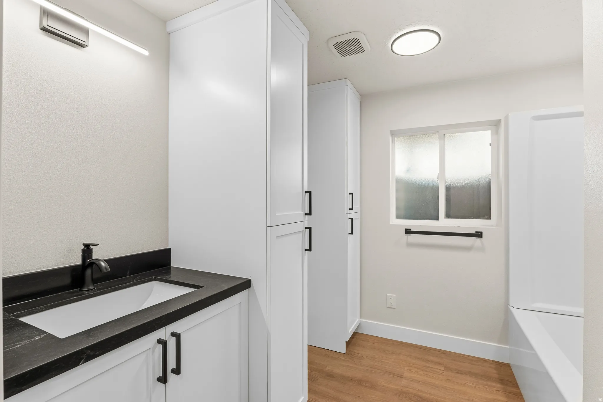 Bathroom featuring a white vanity with a dark countertop and integrated rectangular sink