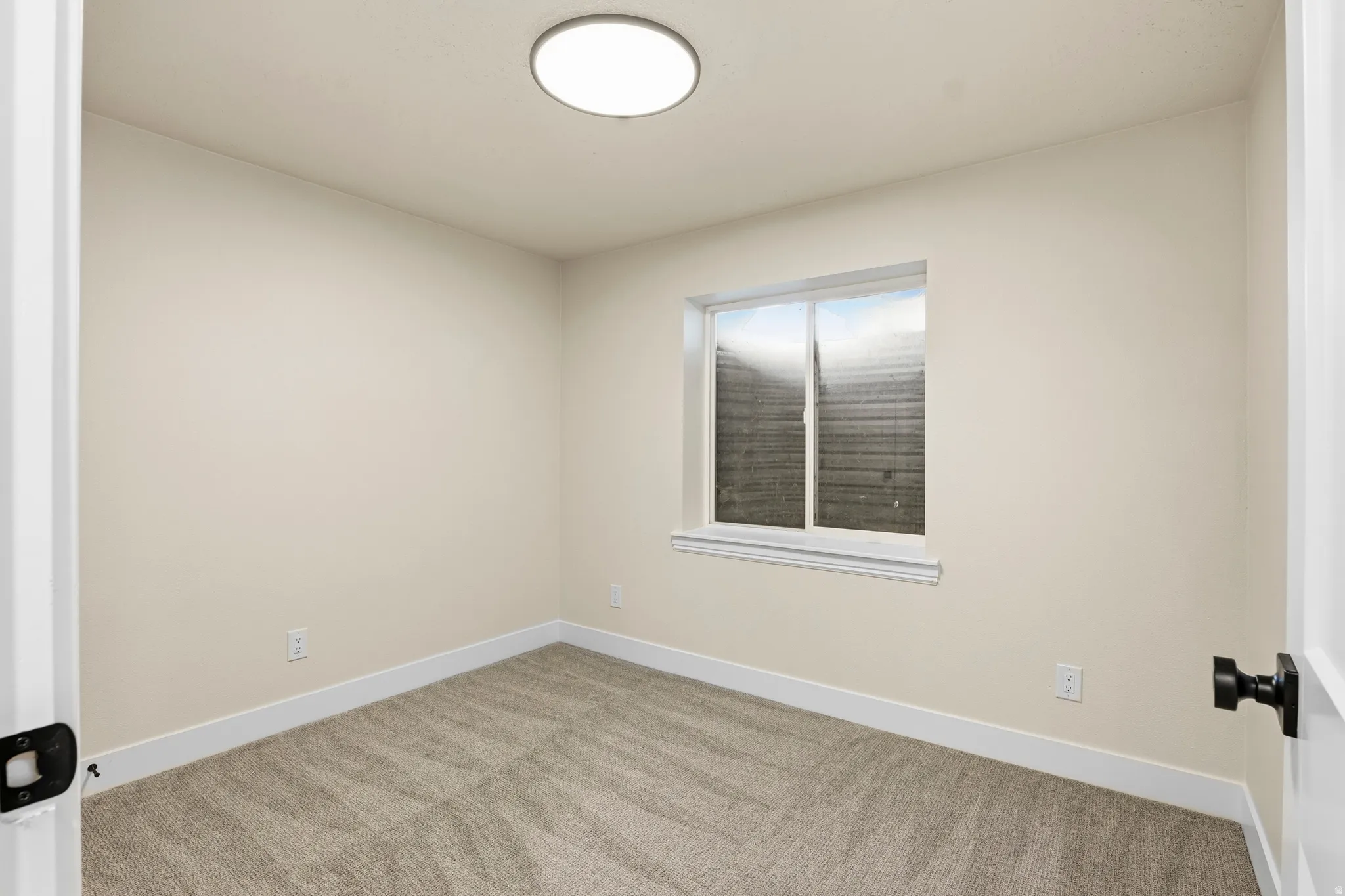 Bright room with neutral wall tones and a window featuring white trim