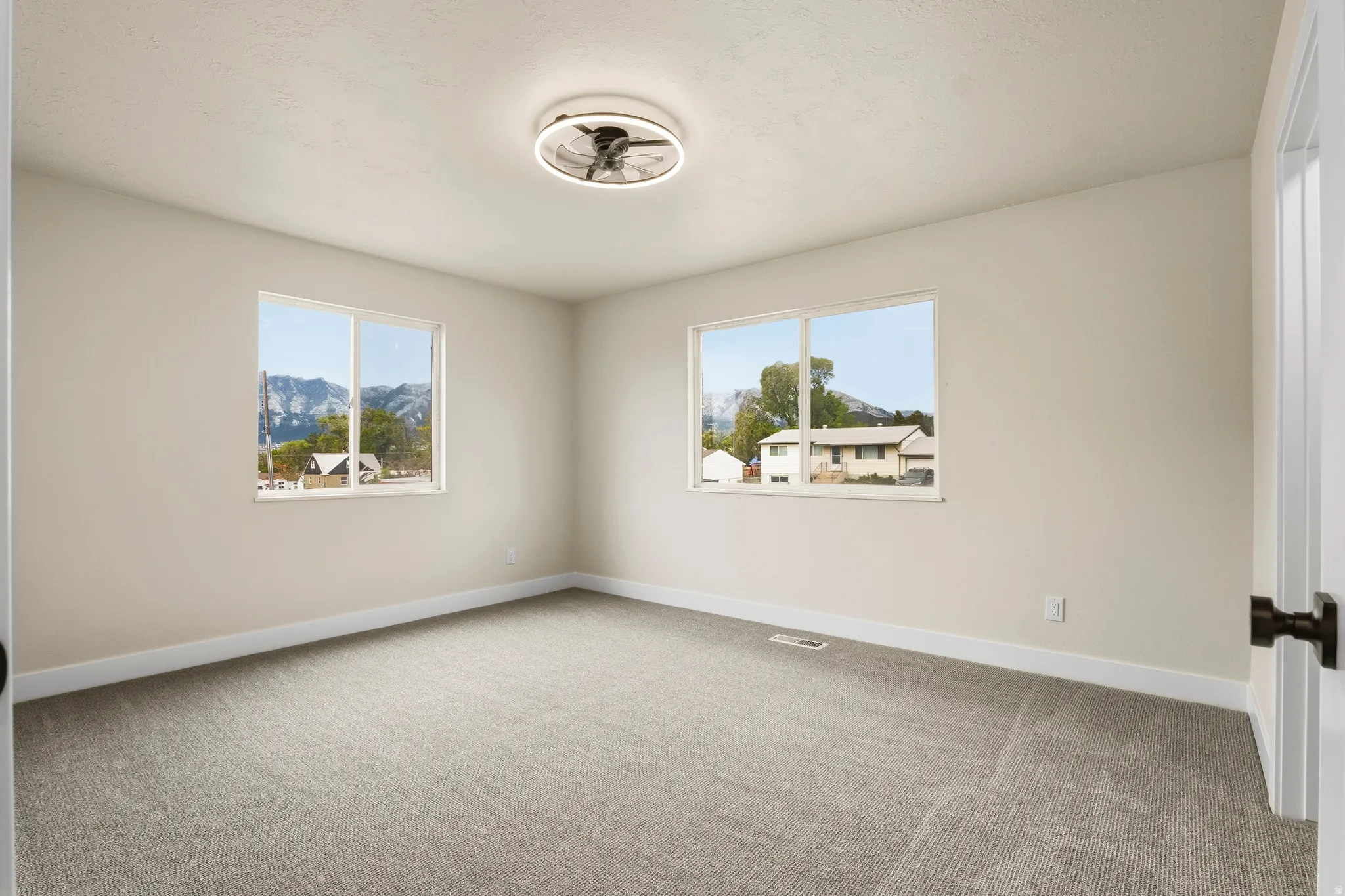 Neutral-toned interior room with gray carpeting and white baseboards