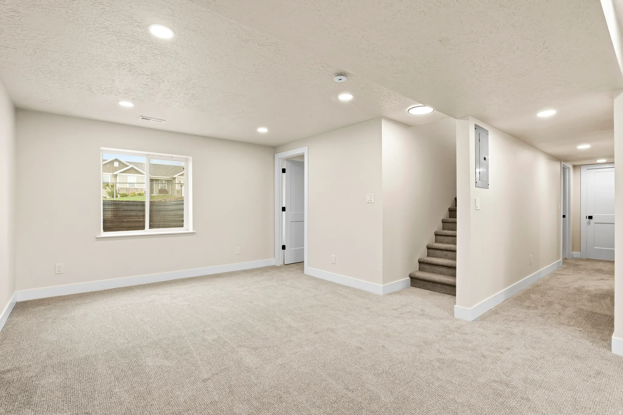 Carpeted lower level featuring recessed lighting, a window, white trim, and a staircase with carpeted treads