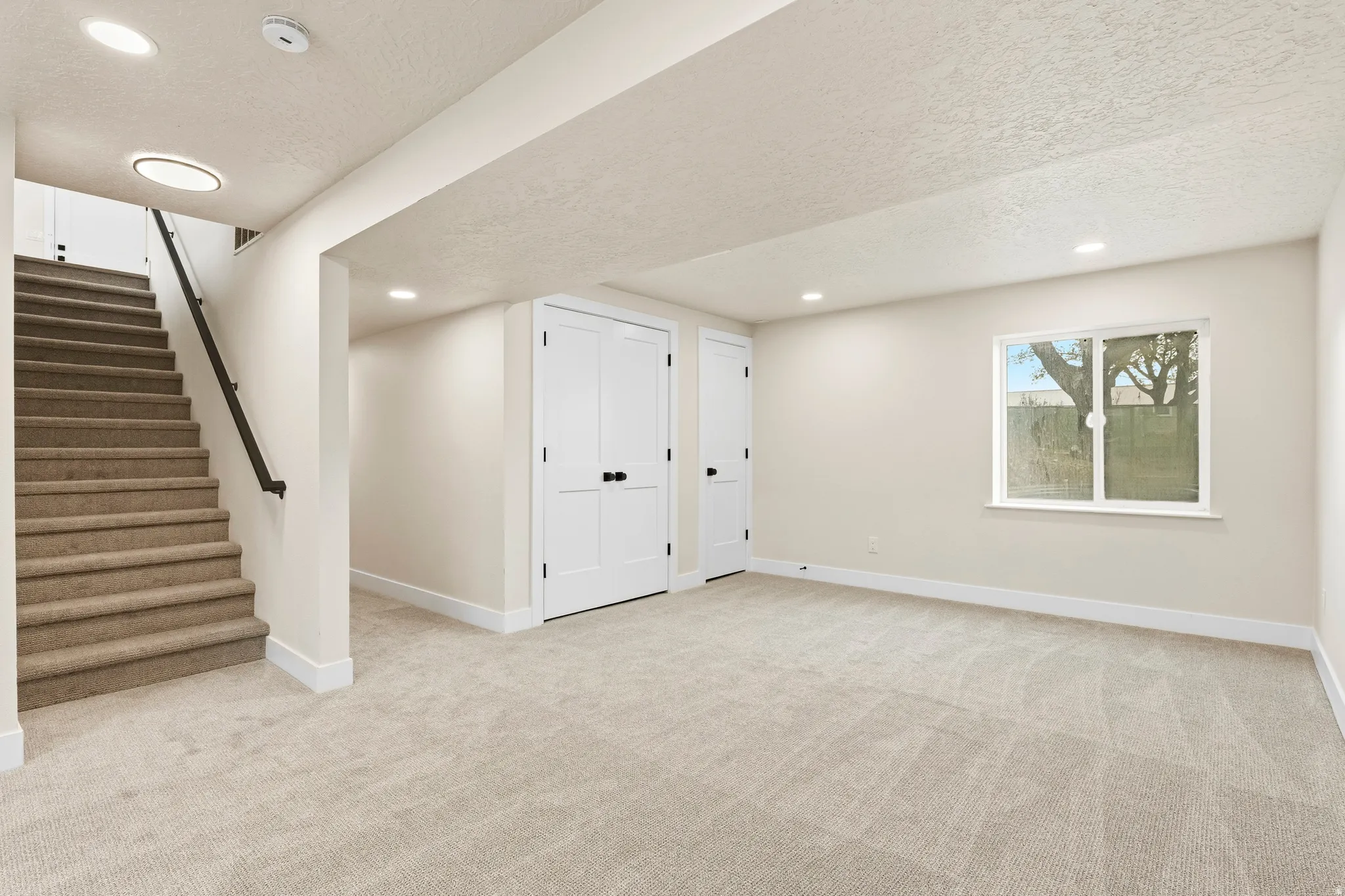 Spacious room featuring light-toned carpet, a window, and recessed lighting