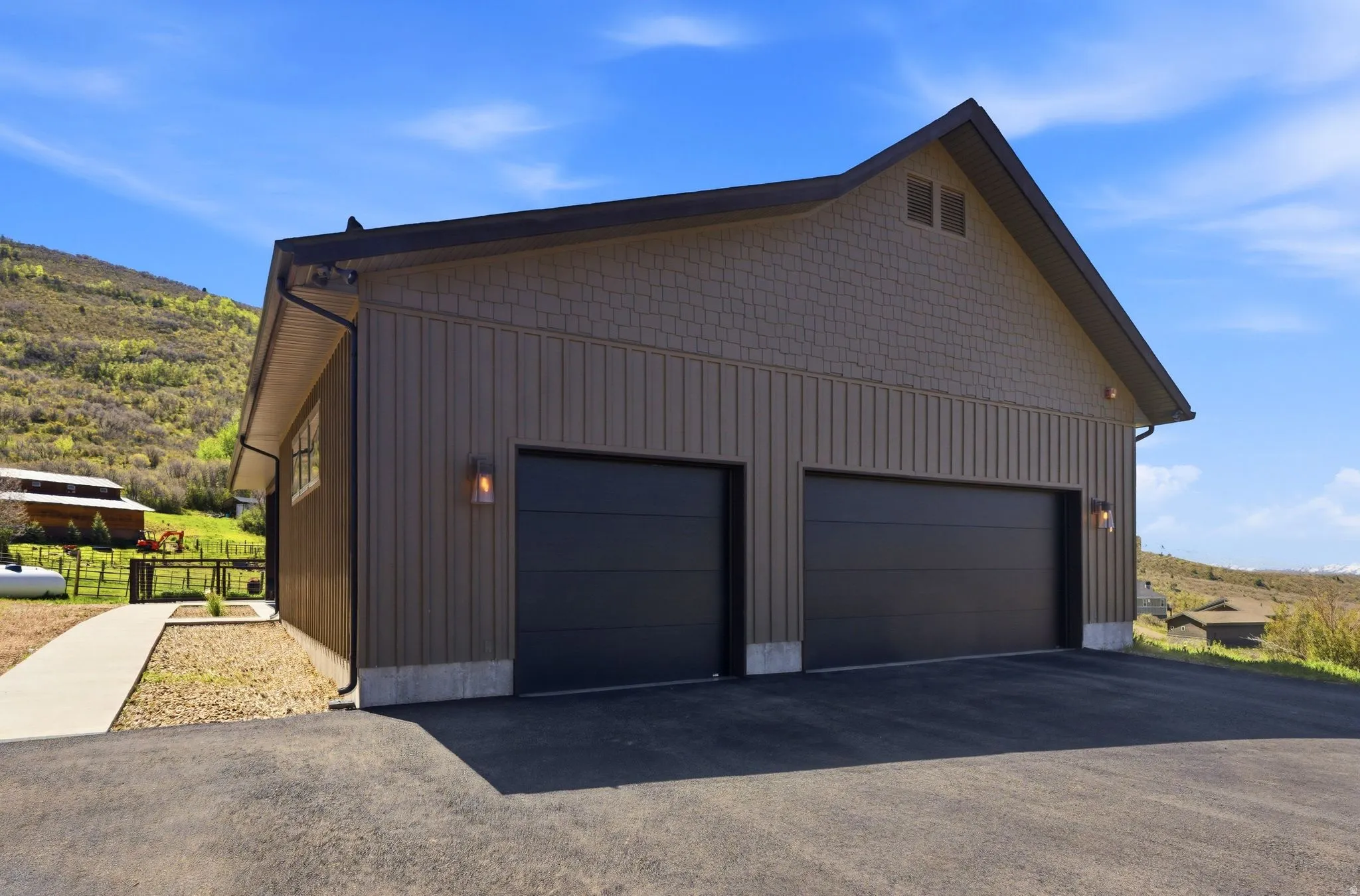 Two-car garage featuring vertical panel siding, horizontal shingle siding, and modern black garage doors