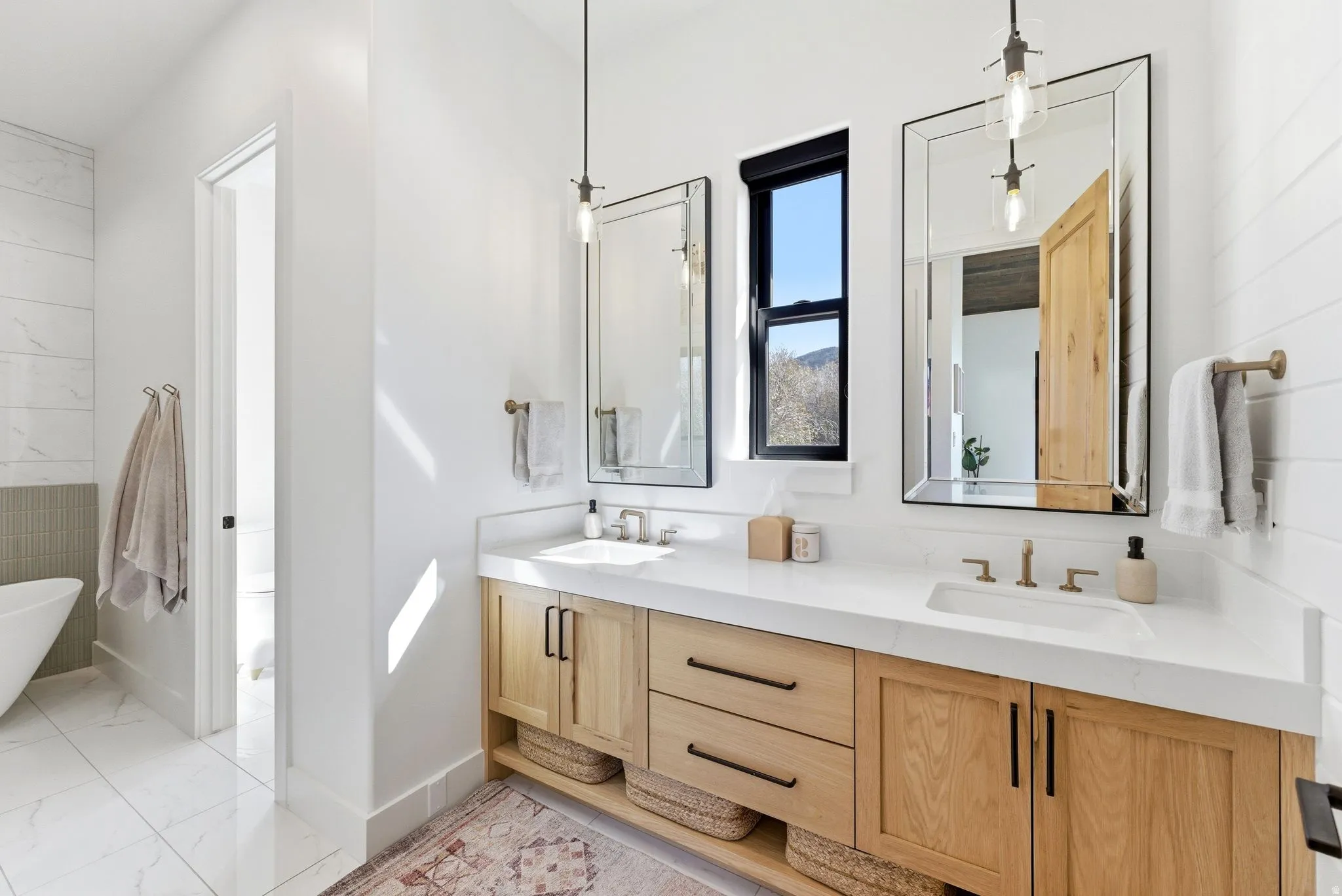 Dual sink vanity with light wood cabinetry, white countertops, and integrated sinks