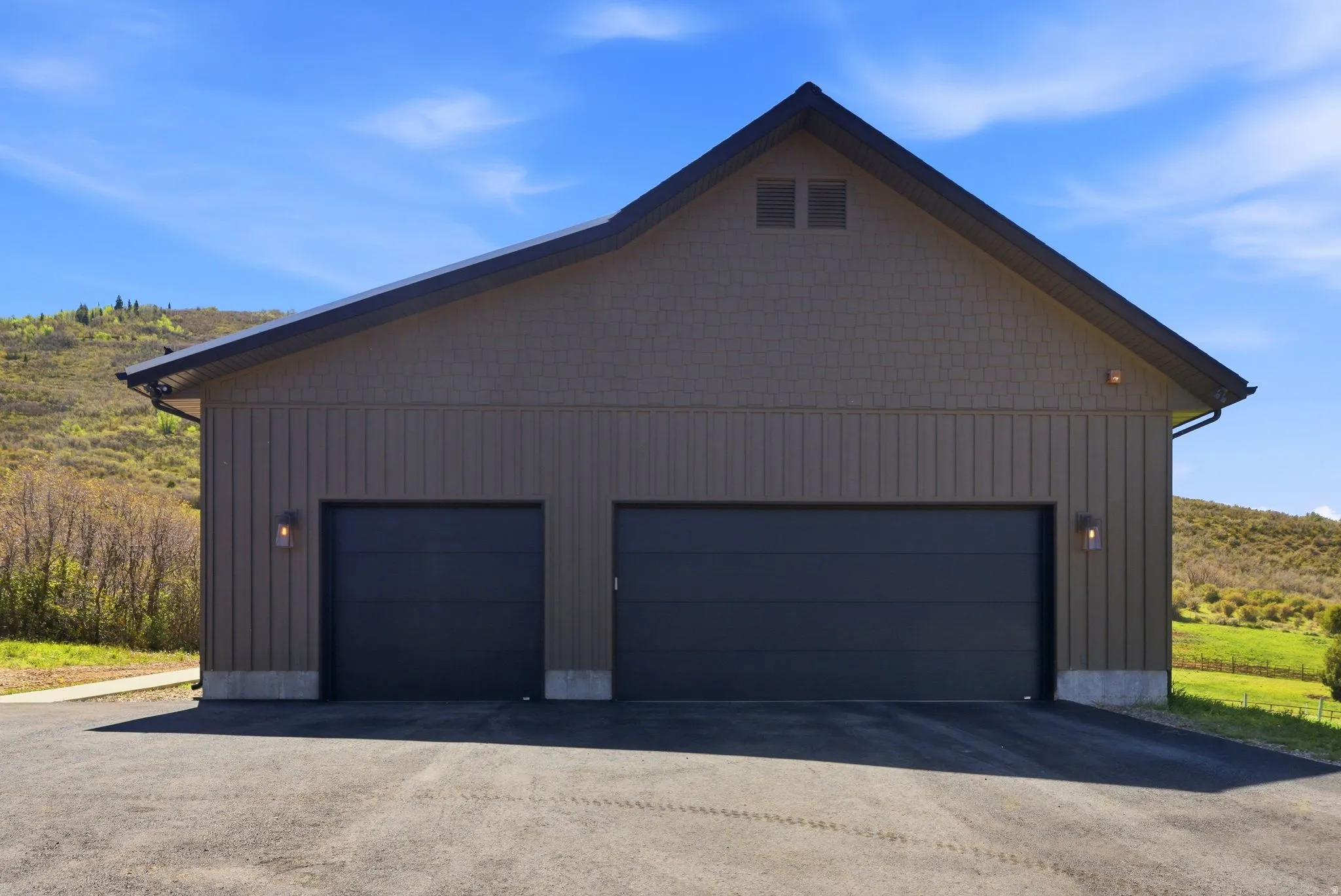 Two-car garage with board and batten siding, shaker shingle gable, and dark gray garage doors