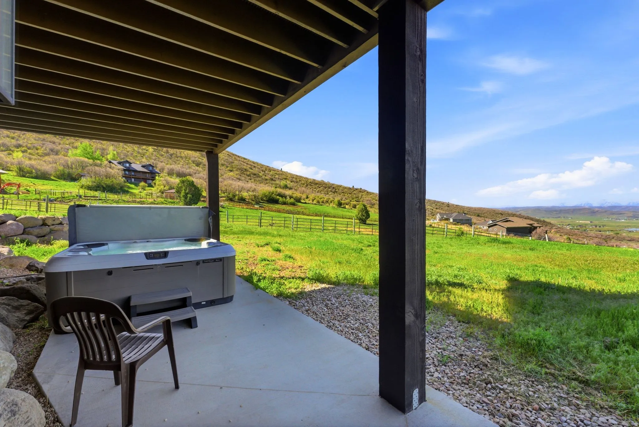 Outdoor patio featuring a hot tub, concrete flooring, and surrounding green landscape