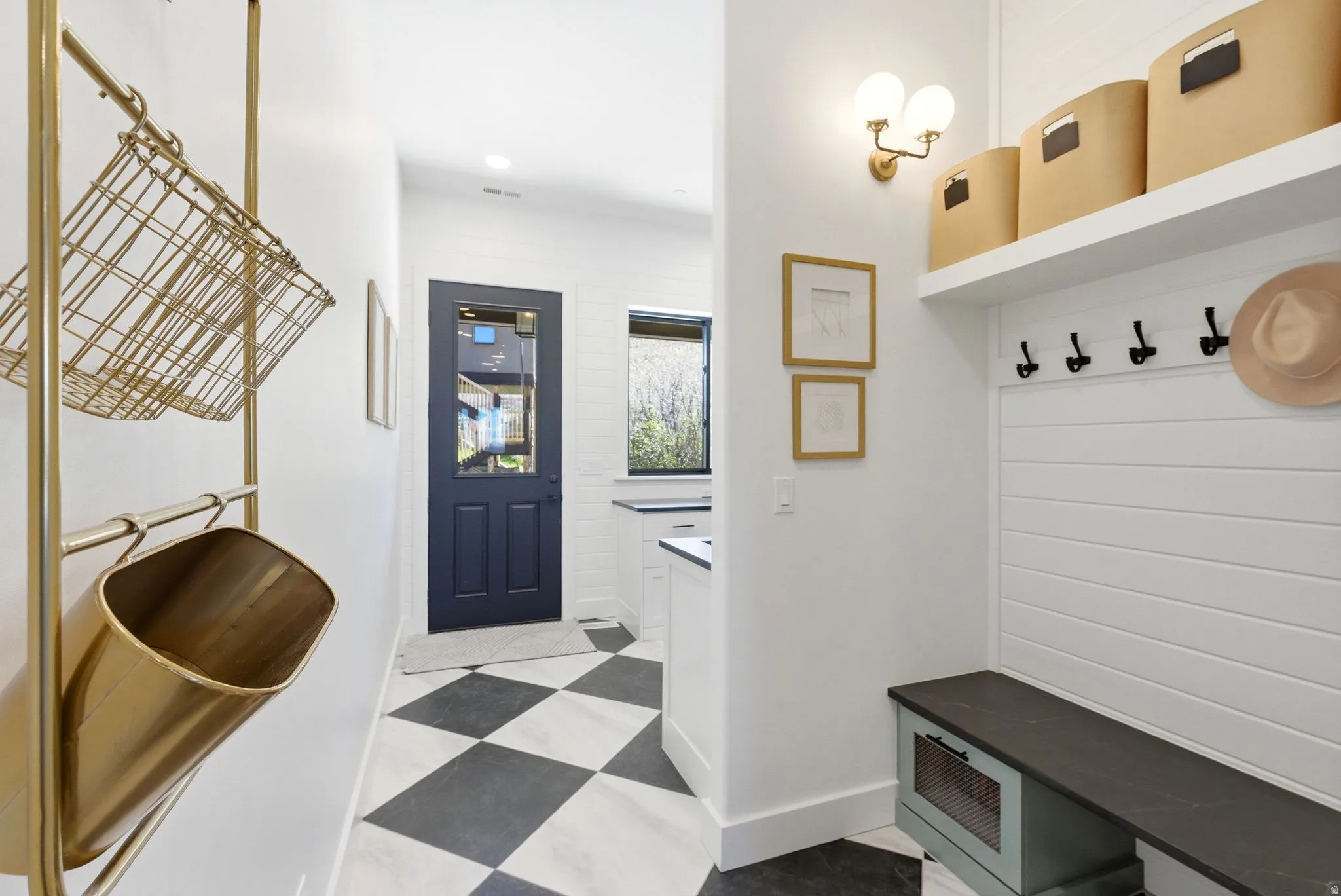 Entryway featuring checkerboard floor tiling, a dark-paneled door with glass, built-in bench seating, shiplap wall paneling, and a wall-mounted light fixture