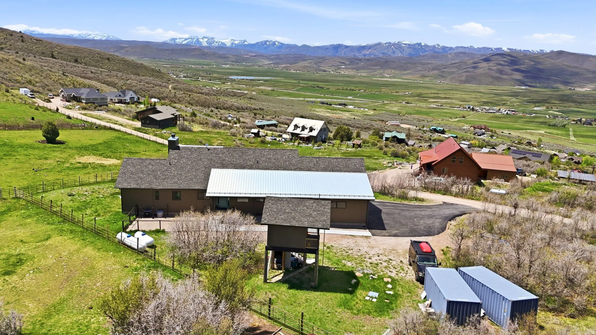 Expansive property featuring a brown-toned residence with a shingled roof and a metal-roofed addition