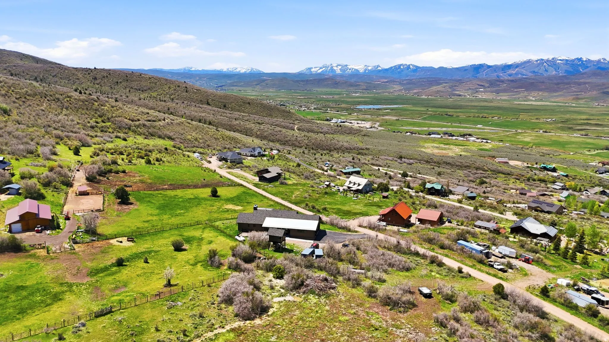 Expansive property featuring rolling hills, varied topography, multiple structures, extensive green space, and distant mountain ranges
