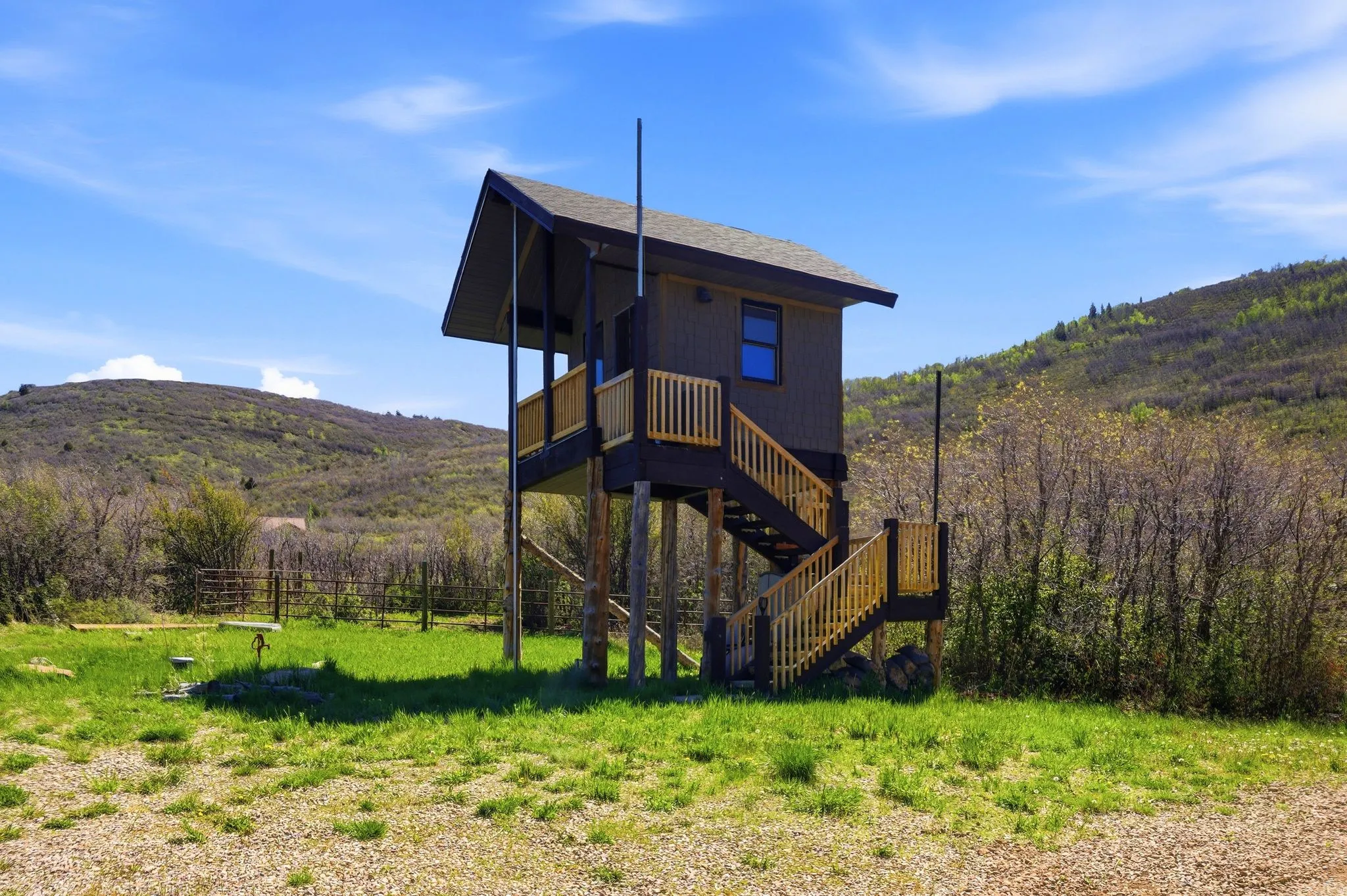 Elevated structure featuring dark siding, a gabled roofline, and a prominent exterior staircase with natural wood railings