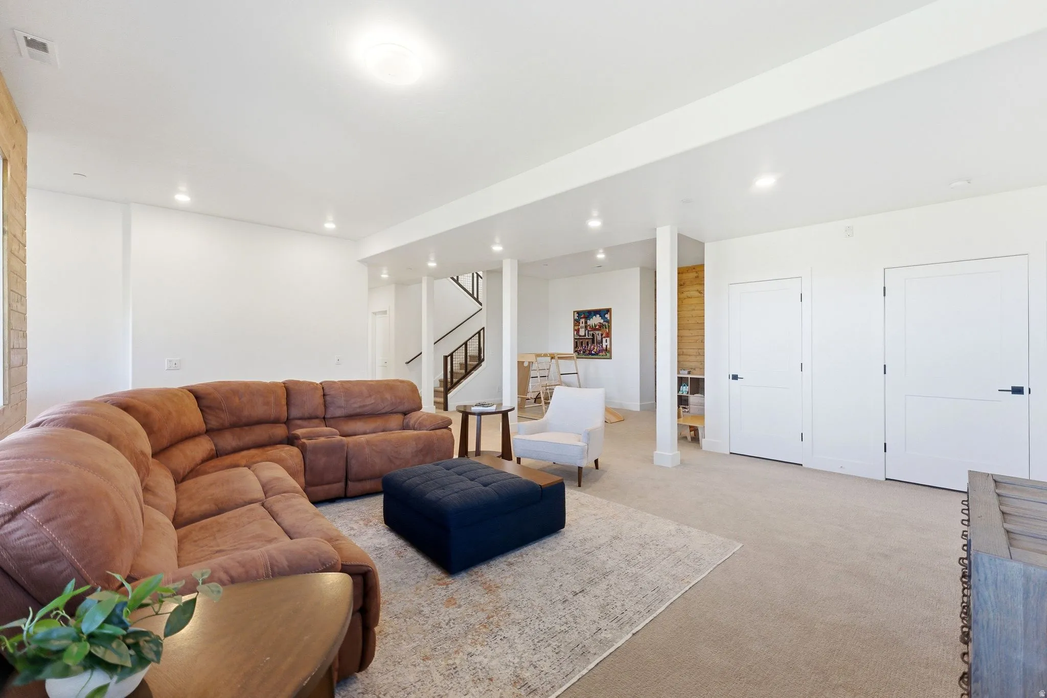 Spacious living area featuring neutral carpet flooring, recessed lighting, and white walls