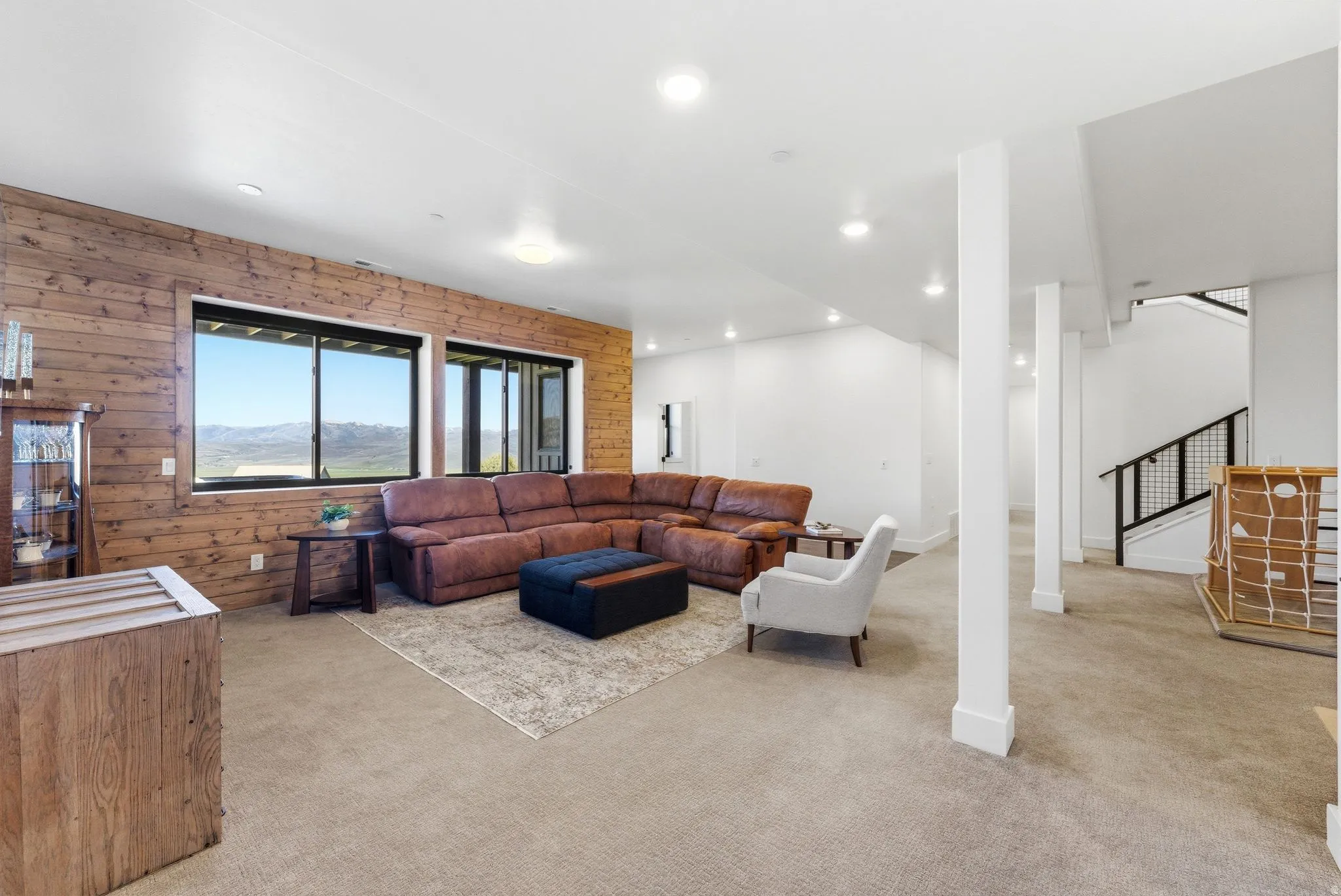 Spacious room featuring a wood-paneled accent wall, large windows, recessed lighting, and carpeted flooring