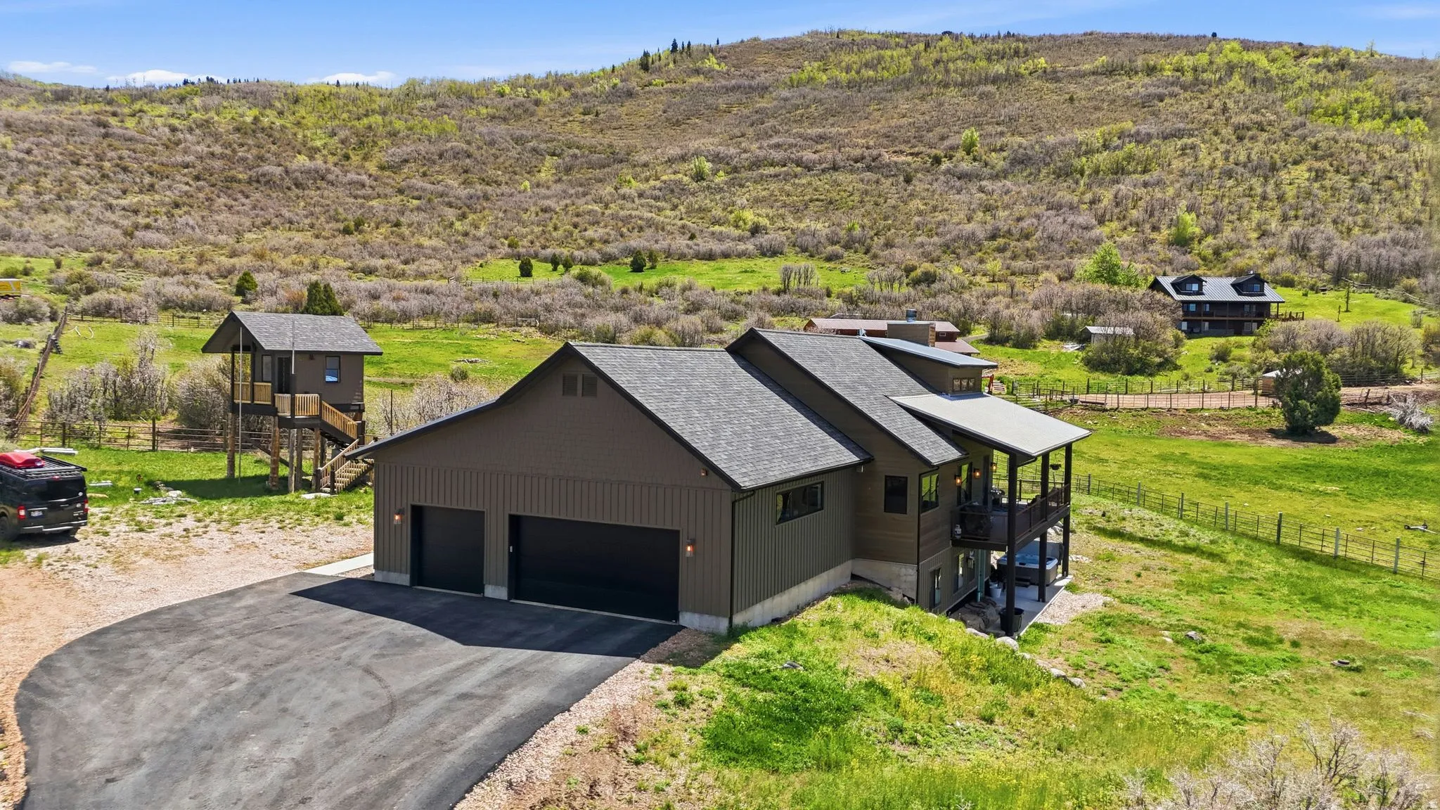 Contemporary mountain-style residence featuring a two-car garage with dark paneled doors