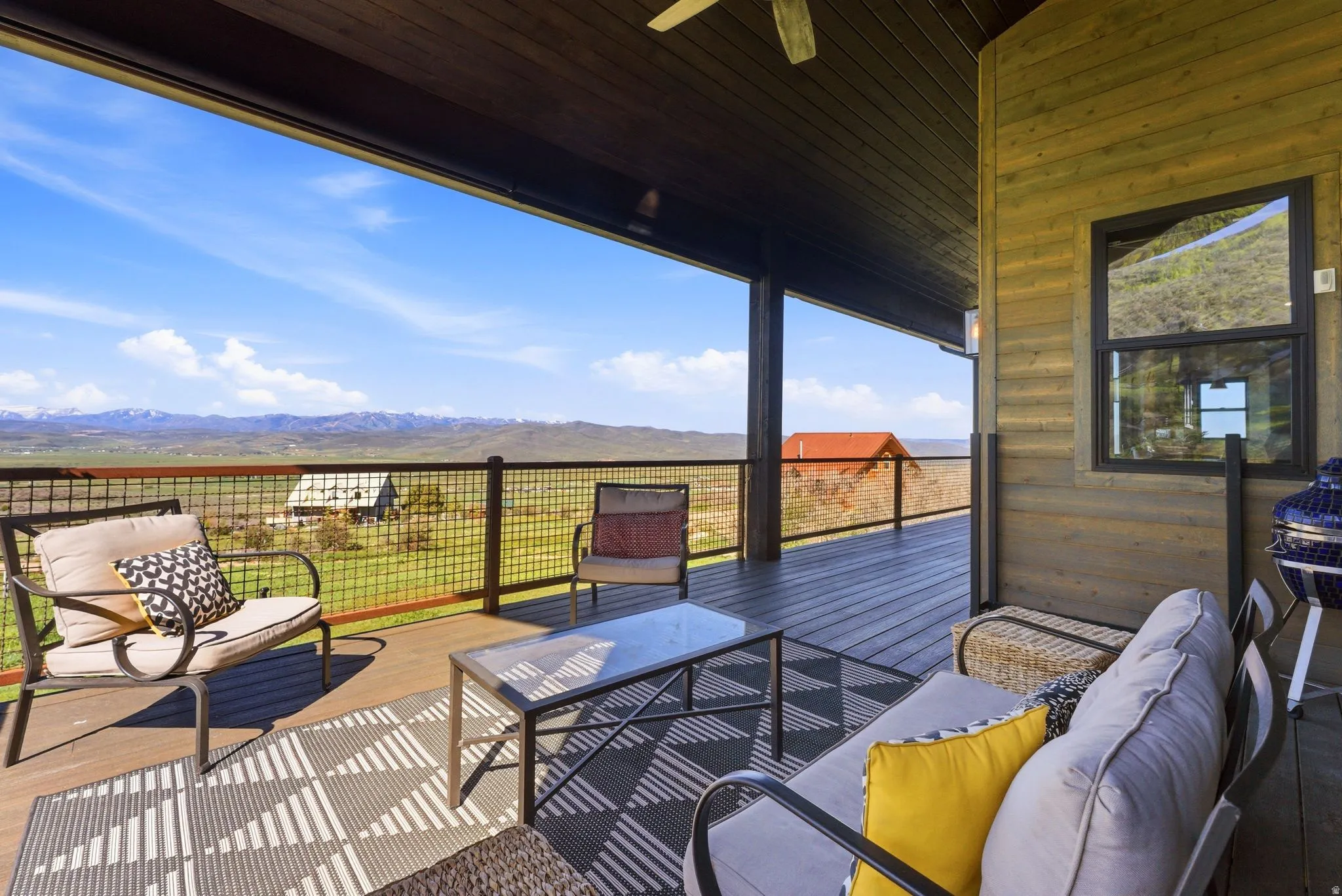 Expansive covered deck featuring wood-finish flooring and a metal grid railing system