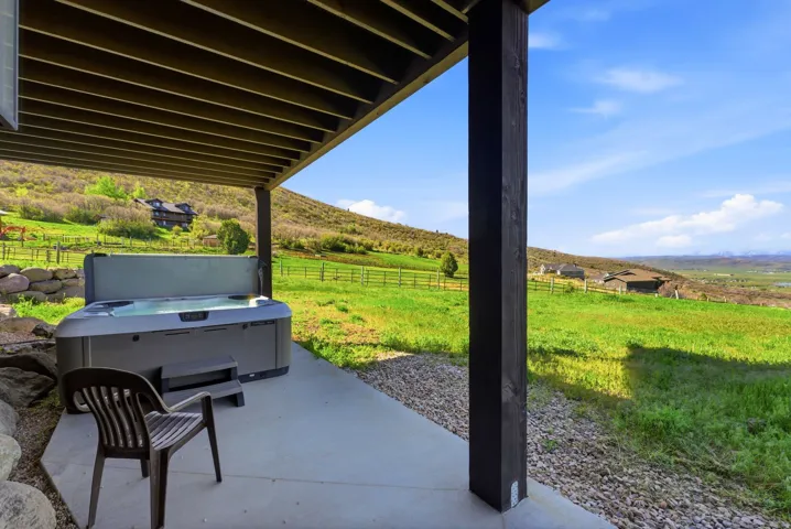 Outdoor patio featuring a hot tub, concrete flooring, and surrounding green landscape