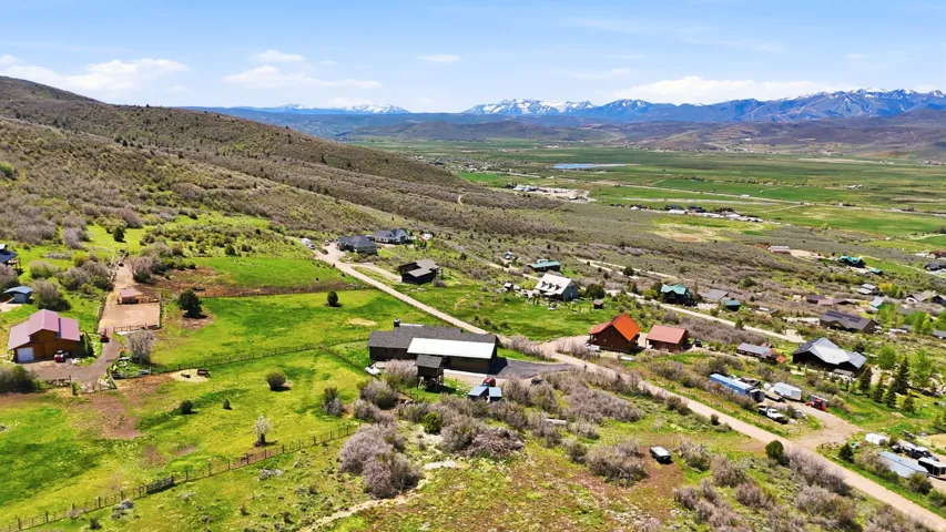 Expansive property featuring rolling hills, varied topography, multiple structures, extensive green space, and distant mountain ranges