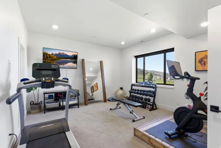 Dedicated fitness space featuring recessed lighting, plush carpeting, a large picture window, and a wall-mounted television