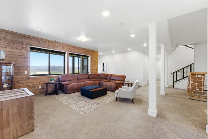 Spacious room featuring a wood-paneled accent wall, large windows, recessed lighting, and carpeted flooring