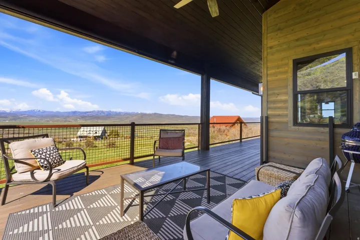 Expansive covered deck featuring wood-finish flooring and a metal grid railing system