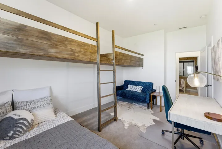 Bedroom featuring a built-in bunk bed system with wood-finish frames and ladders, neutral wall paint, and gray carpeting