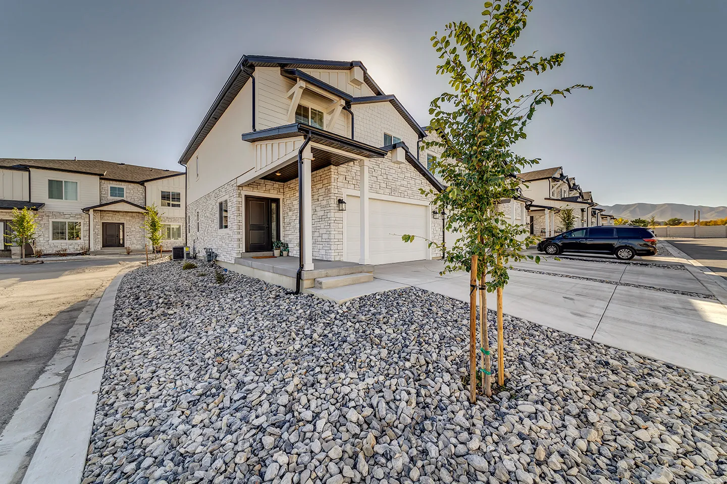 Modern townhome exterior featuring white vertical siding and stone veneer accents
