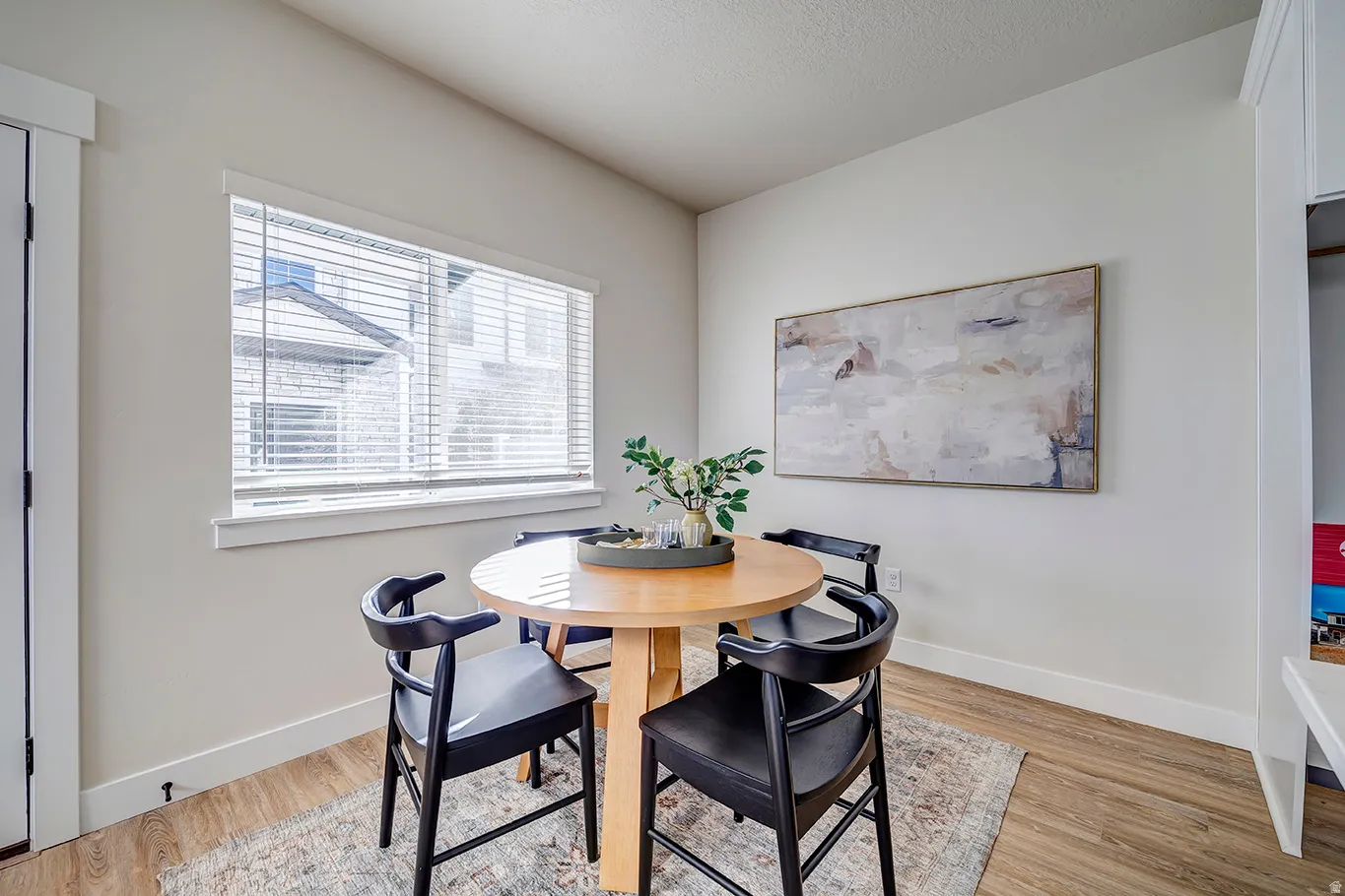 Dining area with wood-finish flooring, a large window with blinds, and white baseboards