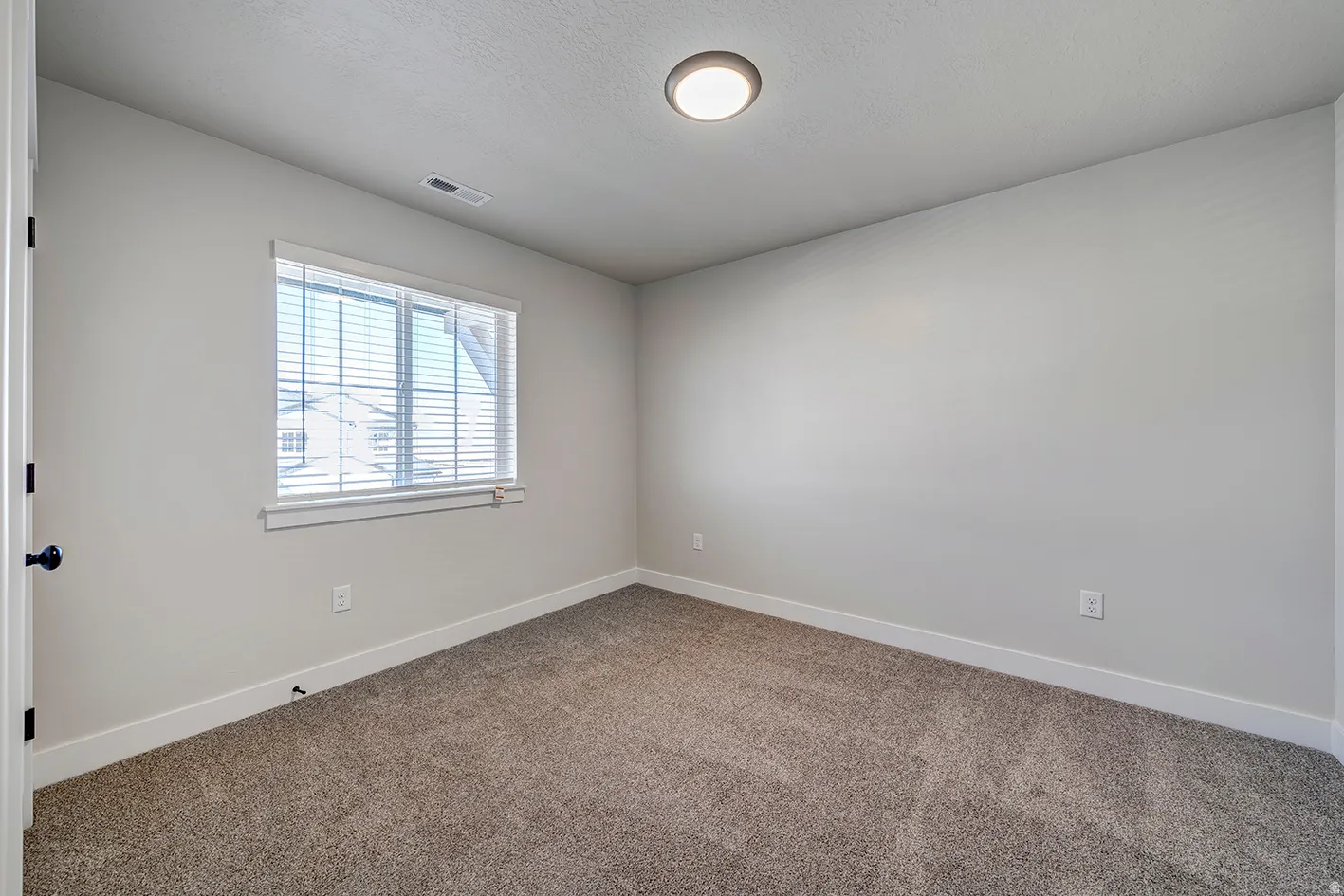 Neutral-toned room featuring a single window with blinds, recessed lighting, and soft carpet flooring
