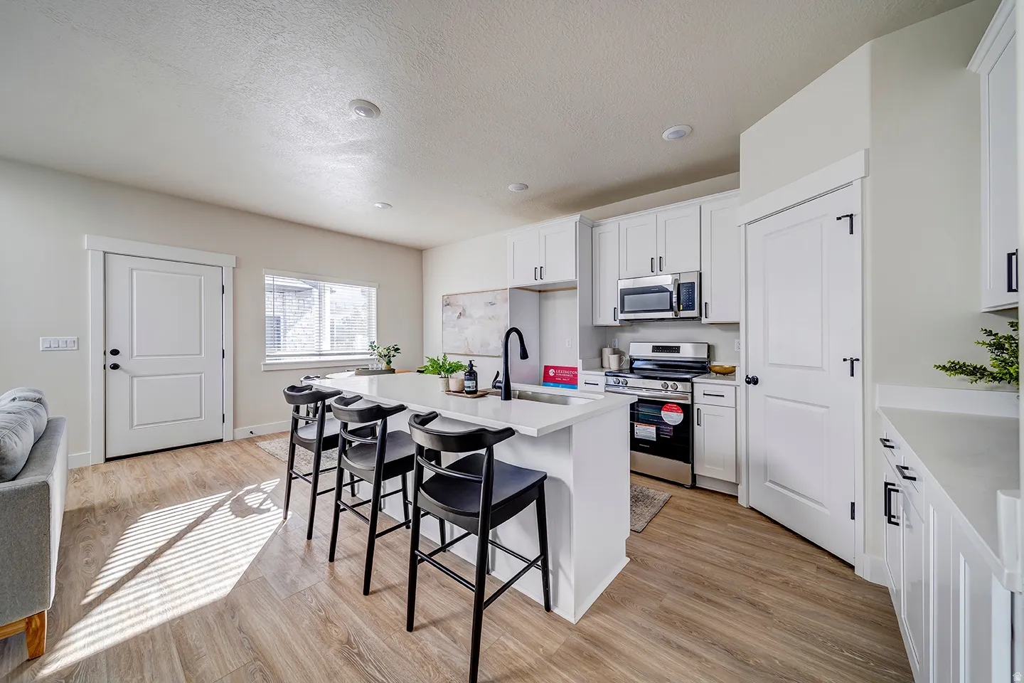 Modern kitchen featuring white cabinetry, stainless steel appliances, a center island with countertop seating, and wood-finish flooring