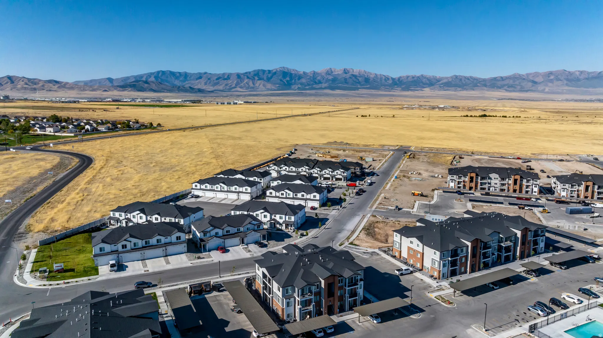 New construction development featuring a mix of multi-story townhomes and apartment buildings with mountain backdrop