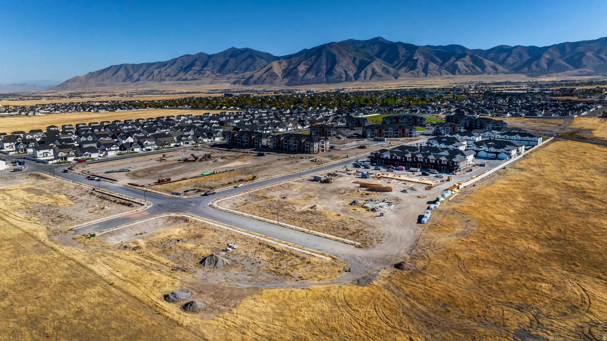Expansive development site featuring graded lots and new residential construction with mountain range backdrop