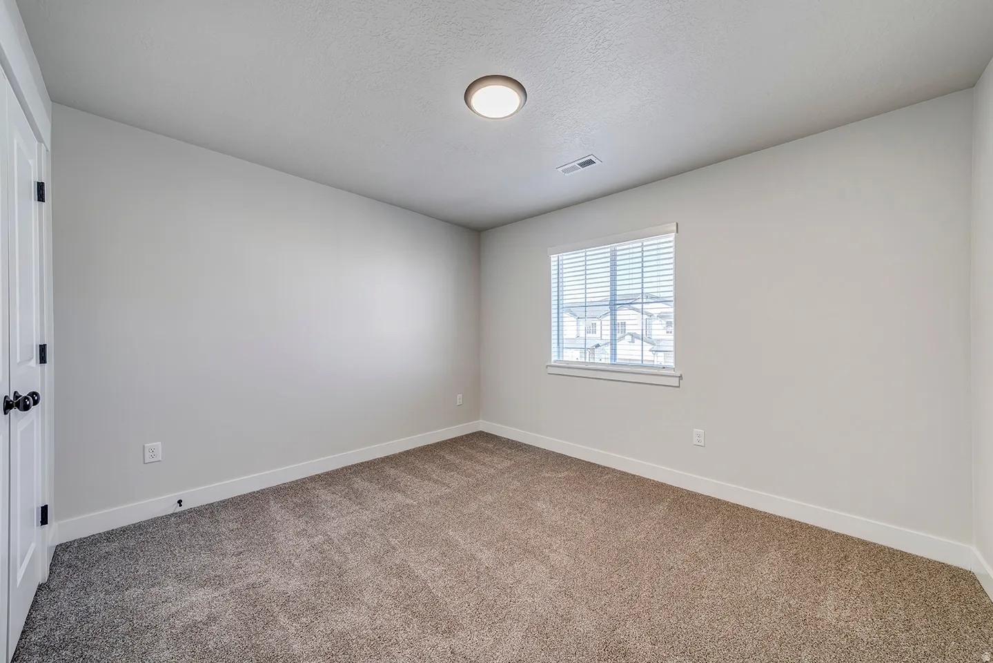 Carpeted interior room with light neutral wall paint