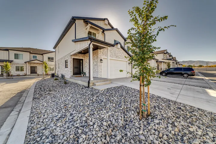 Modern townhome exterior featuring white vertical siding and stone veneer accents