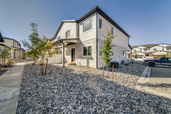 Modern townhome exterior featuring light-colored stucco and stone veneer