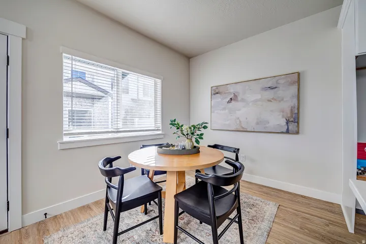 Dining area with wood-finish flooring, a large window with blinds, and white baseboards