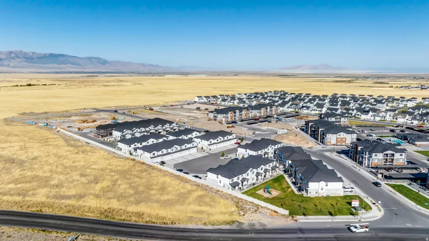 Expansive aerial rendering a developing residential community, featuring multiple rows of newly constructed townhomes and apartment buildings
