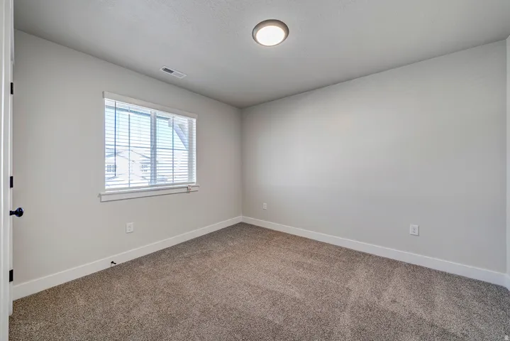 Neutral-toned room featuring a single window with blinds, recessed lighting, and soft carpet flooring